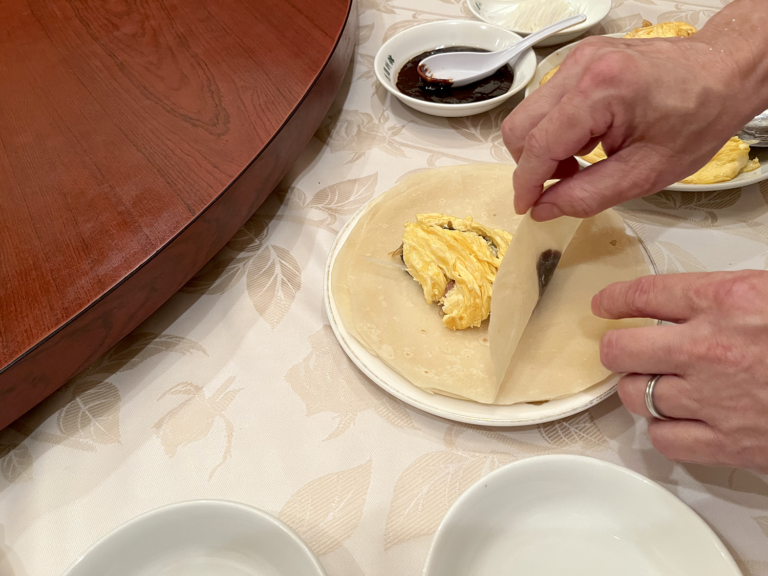 薄餅の中央に甜麺醤とネギ、さらに一口大くらいの野菜炒めを乗せる。まずは具が漏れないよう下の部分から折り、次に左右を折る。