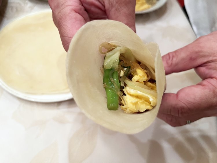 薄餅の中央に甜麺醤とネギ、さらに一口大くらいの野菜炒めを乗せて包む。