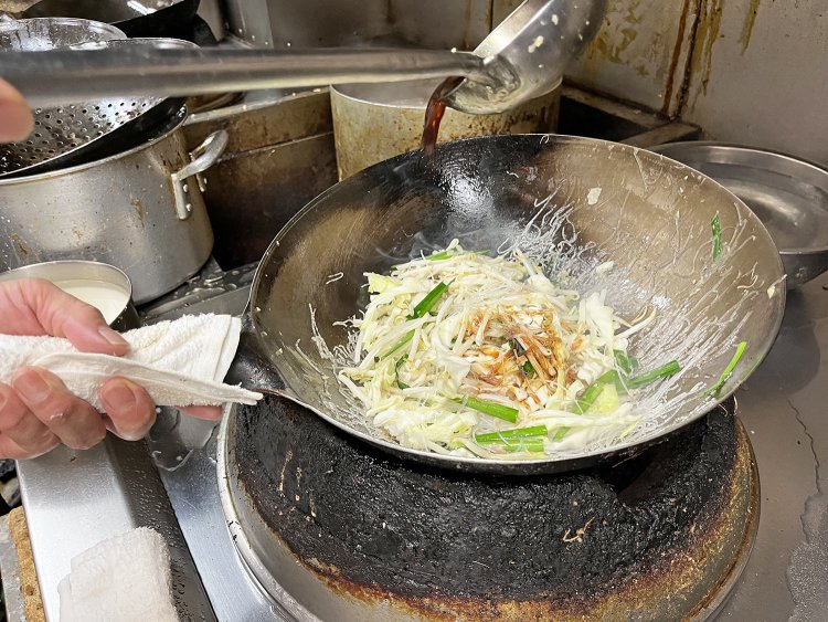 モヤシ、ニラ、キャベツ、豚肉、春雨をショウガが利いた醤油ベースの調味料で手際よく炒める。