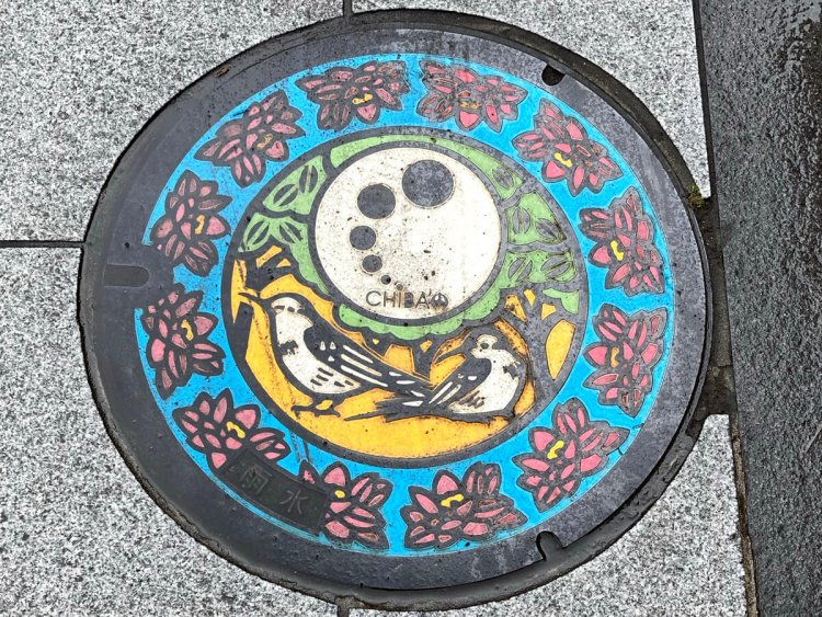 千葉駅近くのマンホール。市の花と鳥「オオガハス」と「コアジサシ」をあしらったデザイン。左下に「雨水」の表記がある。