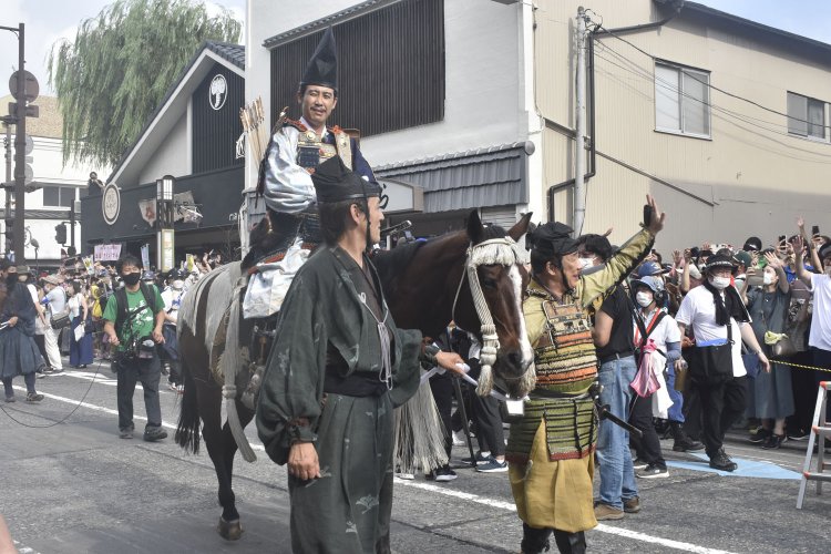 大勢の見物人に驚く馬上の大泉洋さん演じる源頼朝公。馬の轡（くつわ）を取るのは、安達盛長を演じる野添義弘さん（右）。