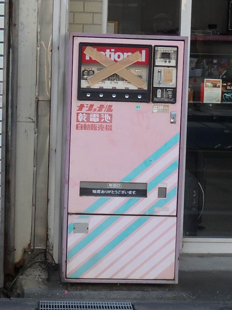 80年代風カラーに彩られた自販機。ガムテープが×印に貼られていて悲しい（浜松・2018年）