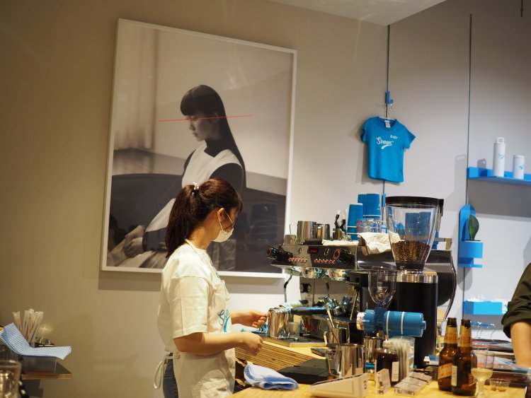 ロゴ入りマグカップやTシャツなど手に取りたくなるオリジナルグッズもロビーで販売。カフェスペースでは本格エスプレッソマシンを使ったコーヒーやラテをはじめ、ビールや軽食も楽しめる。