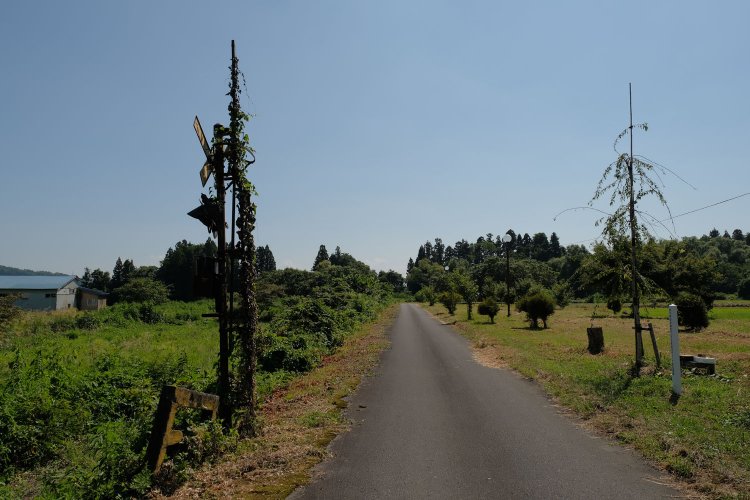 喜多方のほうを見る。小道は先で右に曲がっているが、線路は林となった部分で野辺沢川を渡っていた。転車台の土台も小道が曲がる付近に残されている。