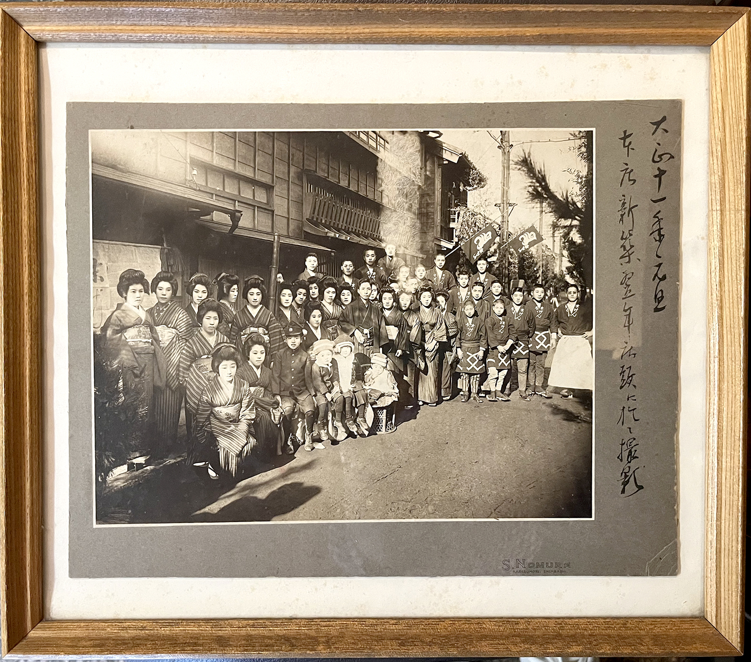 玄関に飾ってある大正11年（1922）当時に店の前で撮った写真。中央で腰に手を当てている男性が創業者の丸源一郎さんだ。