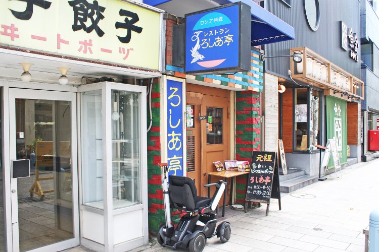 神保町駅A7出口から徒歩1分。カラフルなレンガとブルーの看板が目印。隣は2020年6月に惜しまれつつ閉店した餃子の老舗「スヰートポーヅ」。