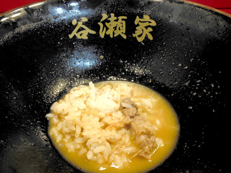 スープにニンニク、一味の醤油漬け、豆板醬を混ぜてご飯を投入。辛味調味料にも負けないスープの味わい深さはおどろき。