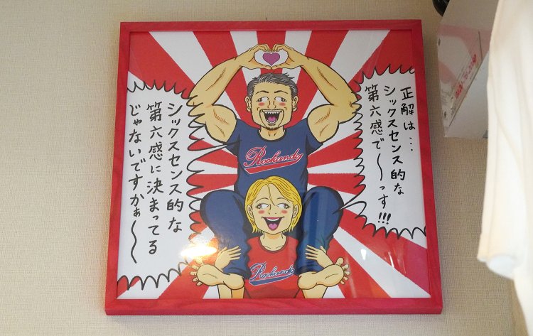 六感堂の「6」は「第六感」！清野さんが教えてくれる。このほかにも店内には清野さんが描いたものが多数。