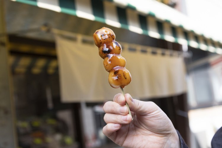 すっきりとした後味のみたらしダンゴ95円。軒先に揺れる白いのれんが昔ながらの風情を醸す。