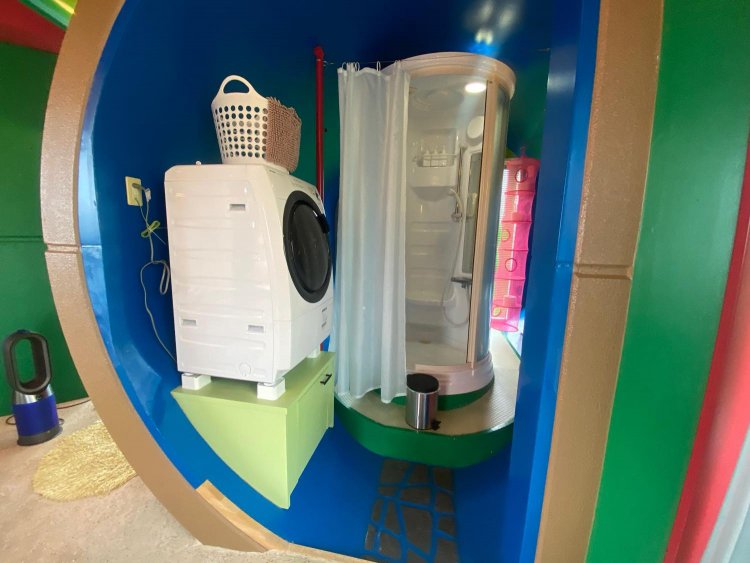 珍しい円柱のシャワールームを中心に、洗面所、洗濯機、奥にはトイレがある。