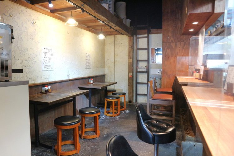 店内はウッディで落ち着きのある雰囲気。カウンター席、テーブル席がゆとりを持って配置されている。