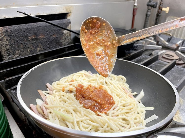 まずはラードでスパゲティを炒め、次に玉ねぎ、ハム、マッシュルームを加え、さらにオリジナルソースとケチャップを加えて炒める。