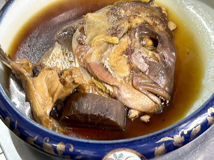 鯛頭煮。煮汁を充分に吸い込んで真っ黒になった大根。
