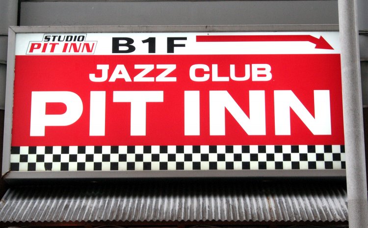 新宿通りを背にさつき通りに入ってすぐ右手、ラーメン屋の上に掲げられた案内看板。このすぐ先にあるビルの地下が『新宿PIT INN』だ。