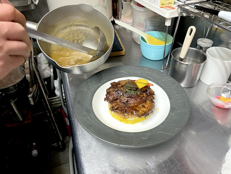 最初に焼いた牛バラ肉とピクルスをトッピングし、スープのようにシャバシャバとしたカレーをたっぷり注いだら完成だ。