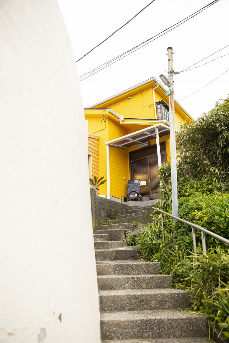 山に張り付く黄色い家が目印。集落の小径を抜けて石段を登るべし。
