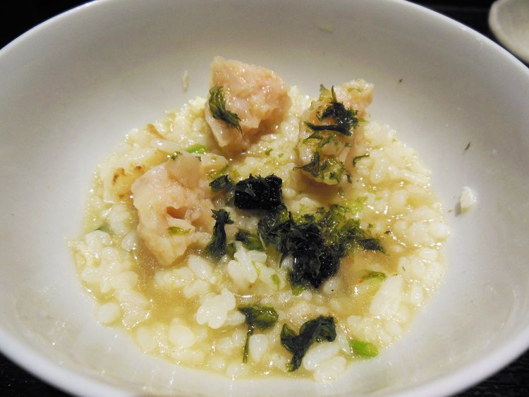 薬味として出される油で揚げた黒いキューブ上の香味野菜で香り付けして、細かくした鯛のつみれと一緒にいただく。