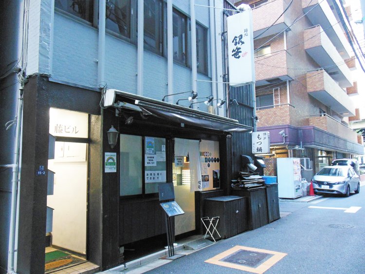 蓬莱橋下の角地に建つ丸みを帯びたミラーガラス張りの銀座COMビル裏手にある。