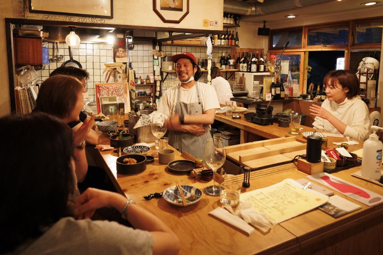 笑顔咲くコの字カウンターとテーブル2卓。「しっかりと下味をつけたからあげやおでんもぜひ！」。