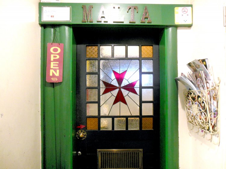 マルタ十字のステンドグラスが施された扉。横開き扉の取っ手部分にもマルタ十字が刻まれている。