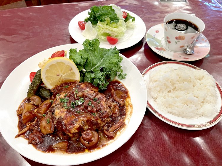 こんがり焼けたハンバーグは、具だくさんのデミグラスがたっぷりかけられて登場。