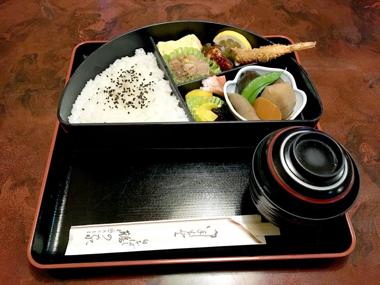 鶴の家の料理オールスターが並ぶ半月弁当。人気メニューがいっぺんに楽しめる。