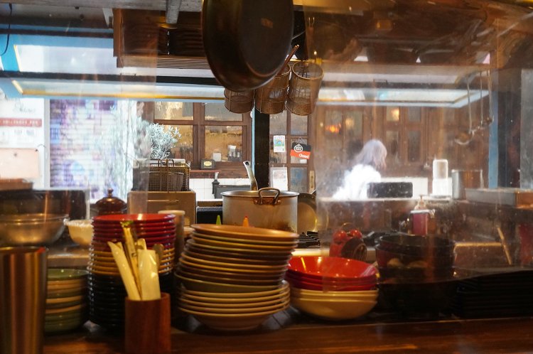 カウンターからキッチンを眺める。窓には商店街を歩く人が見える。