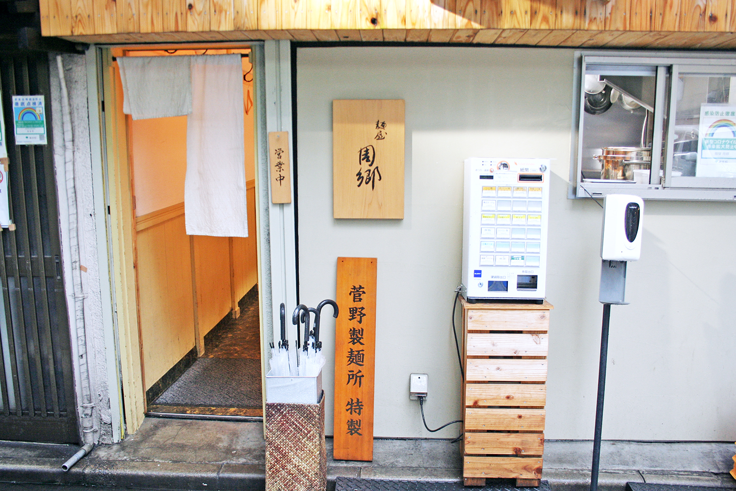日本料理店の趣の外観。券売機の横の窓から厨房が見える。