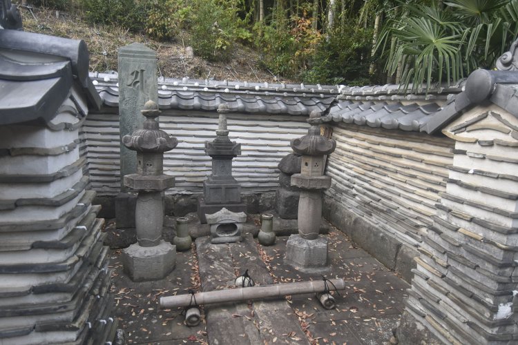 灯籠の後ろに右側に五輪塔、中央が宝篋印塔、左側に板碑が並ぶ。