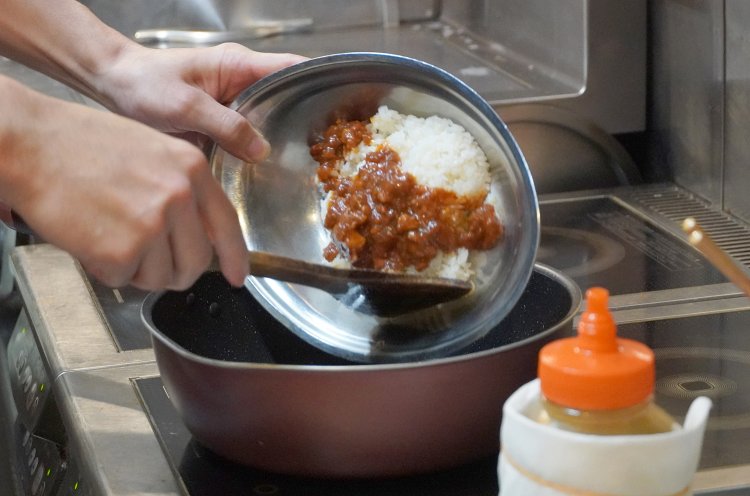 ごはんとチキンライスのソースをフライパンに入れて……。