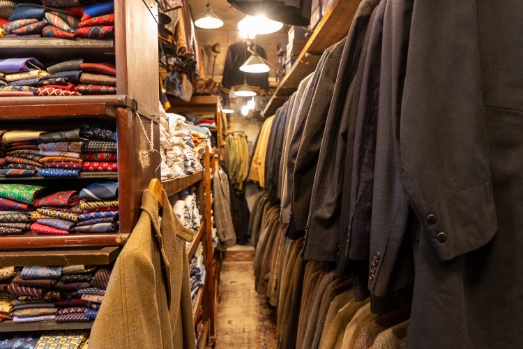 『WHISTLER』の奥にある通路。テーラードのジャケットにネクタイ、シャツなど。天井付近からはレザーのジャケットが吊り下げられている。