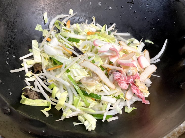 野菜や豚肉、アサリ、カマボコなどの具材と醤油など調味料を加えて手早く炒める。ごま油がいい香り！