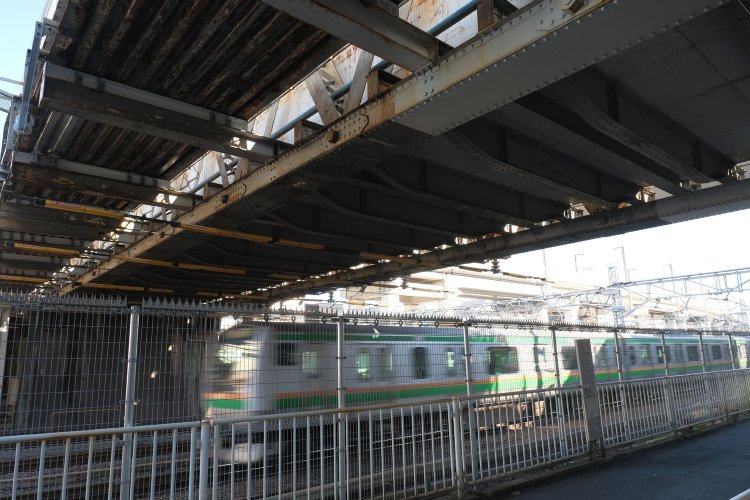 100歳以上のポニーワーレントラスの真下をE233系が颯爽と通過していった。歩道橋はH型鋼をトラスに差し込んで支えにしている。最低限の改良で済んだ様子がうかがえる。