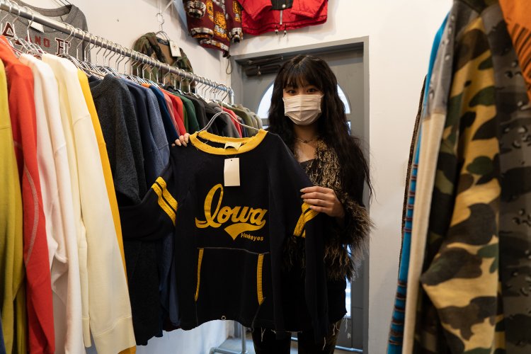 店長の山之口華緒里さん。手にしているのはアメリカの大学フットボールチームのスウェット。