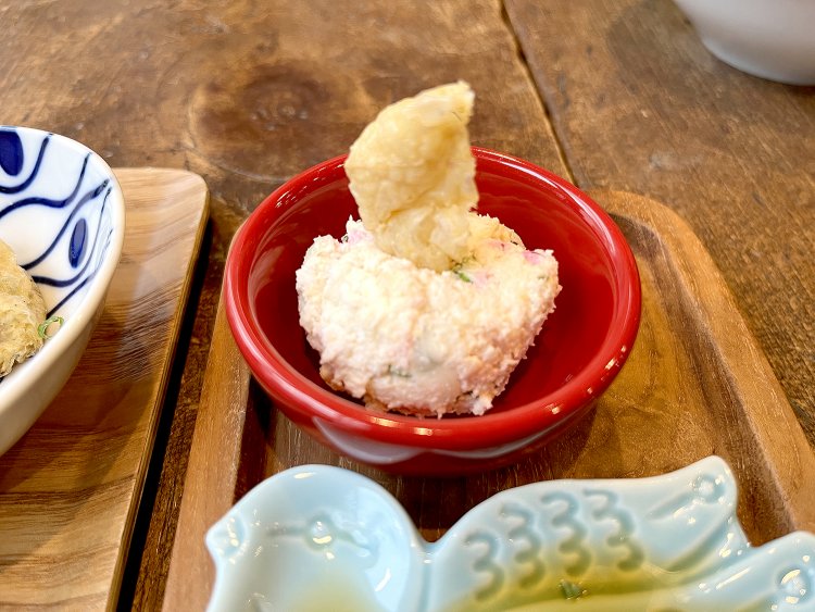 おからのサラダ。タマネギやキュウリとともにマヨネーズで和えてあり、あっさり食べられる。ニワトリのトサカのように逆立った油揚げもカリカリでおいしい。