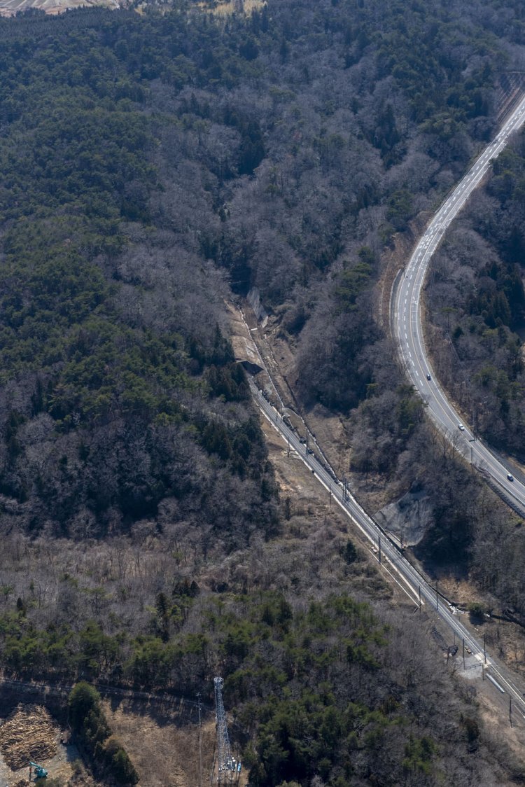 富岡側。除染作業が終わり、線路の復旧工事が行われており、道床のバラストが真新しい灰色だ。現行線から右へ分岐するのが旧線と金山隧道。右手は国道6号線。