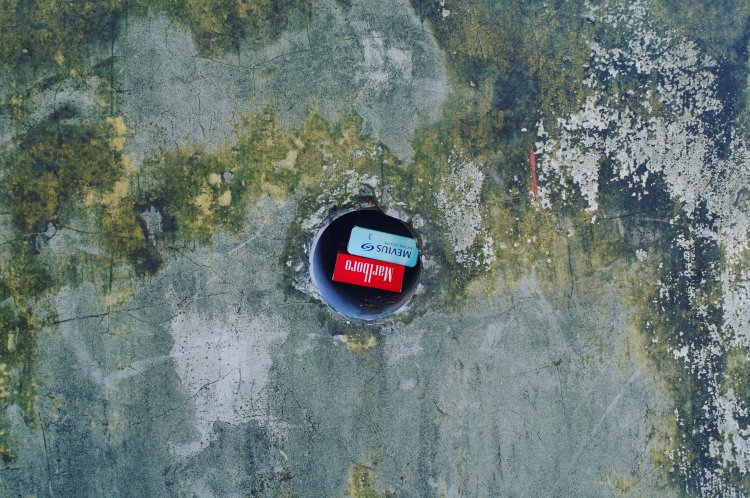 紅白のタバコの箱が几帳面に収納された水抜き穴。