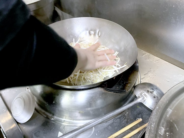 えいやっ！　と中華鍋に投入されたもやし。これでも並サイズだ。