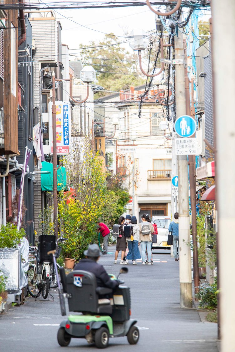 昔ながらの味噌屋や居酒屋が並ぶ根津観音通り商店会。下校中の子供が立ち話。