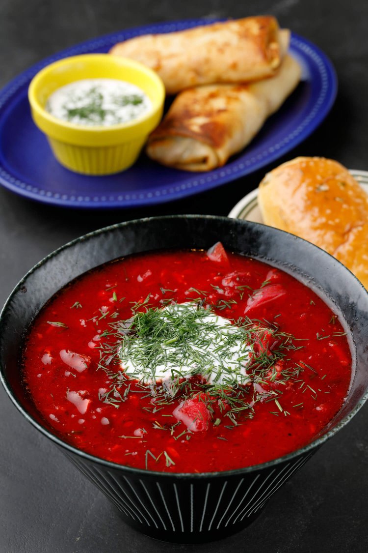 ビーツやトマト、玉ねぎなど具材たっぷりのボルシチ1000円。「東部は牛肉を使うことが多いです」とビクトリアさん。ウクライナ風クレープのナリスニキ700円（写真奥）も人気の定番メニュー。