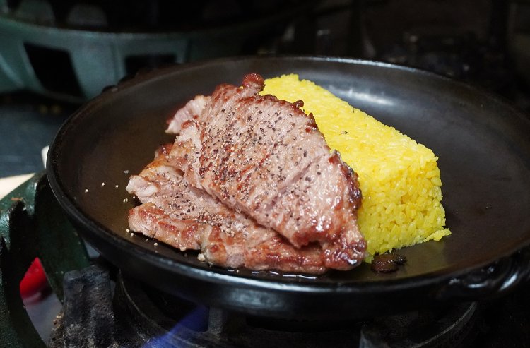 こんがり焼いて切った豚肉をターメリックライスとともに陶板に載せて、