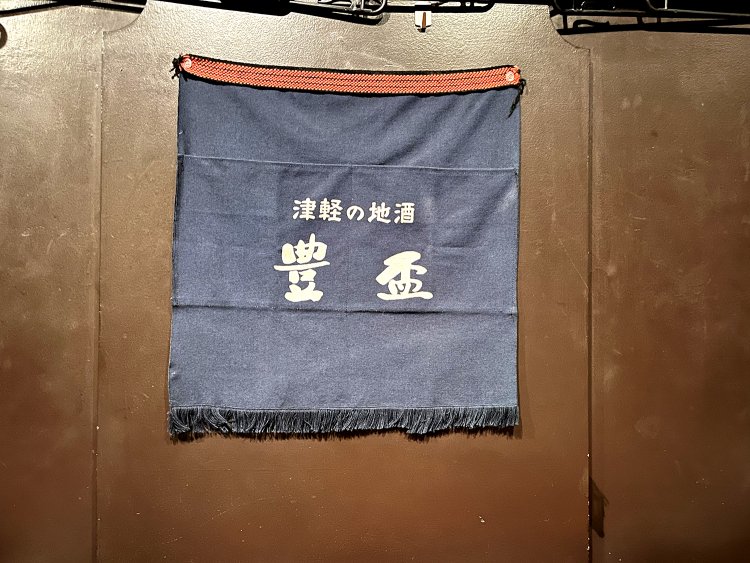 地酒のネーミングが入った前掛けをタペストリーに。味わいがある。