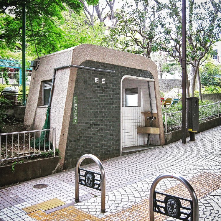 お菓子のような形をしたトイレ。周囲の木々に落ち着いた色味が溶け込む。「便所」の二文字が潔い。