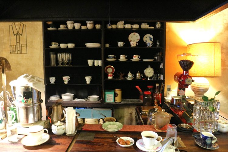 マスター、常連さんの会話が弾むカウンター席。棚にはいろいろな種類のカップがずらりと並ぶ。