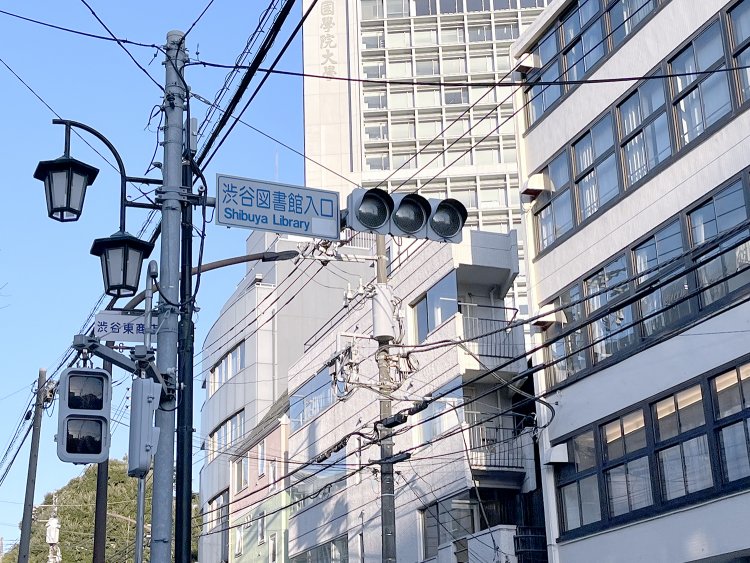標識の奥に見えるのは國學院大学の校舎だ。