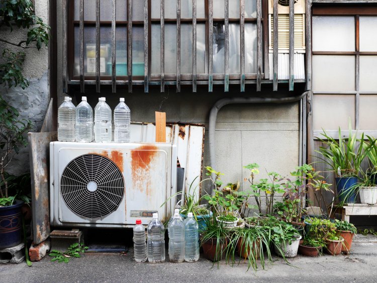鉢植えやペットボトルと共に、風景に溶け込んだ室外機。