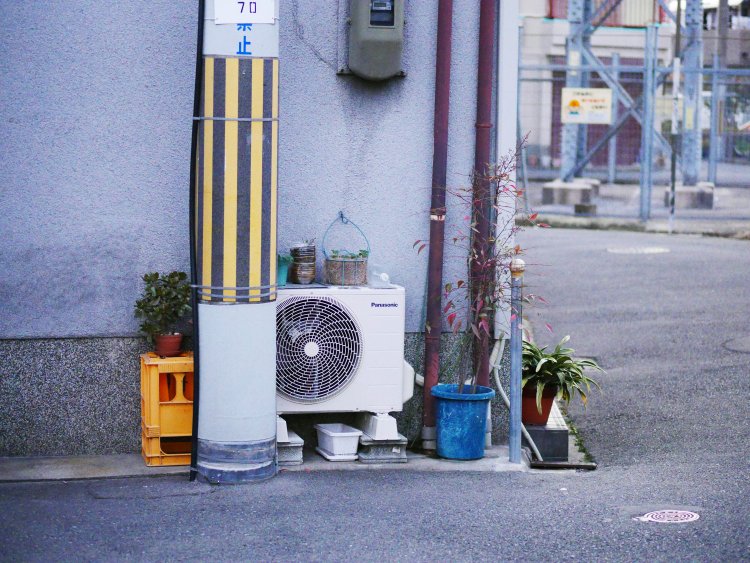 電柱の陰からひっそりと顔を出す室外機。