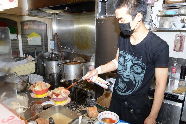 丼のチャーシューを炙る佐々木さん。