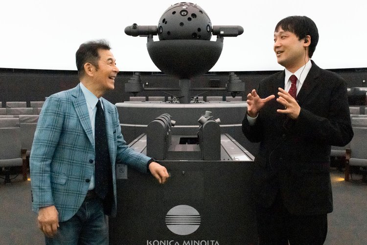 プラネタリウム投影機の前で、星空解説員の田畑勇一さんと。