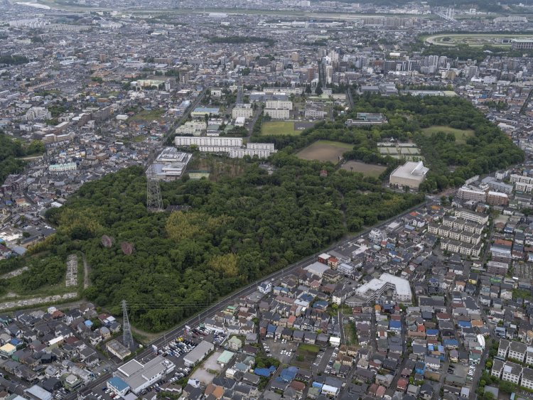 北西方向から。最後まで米軍基地として残されたのは手前の森となった箇所。２基のパラボラアンテナが異様であるが、その近くの細長い痕跡には団地が建っていた。2021/5/11撮影